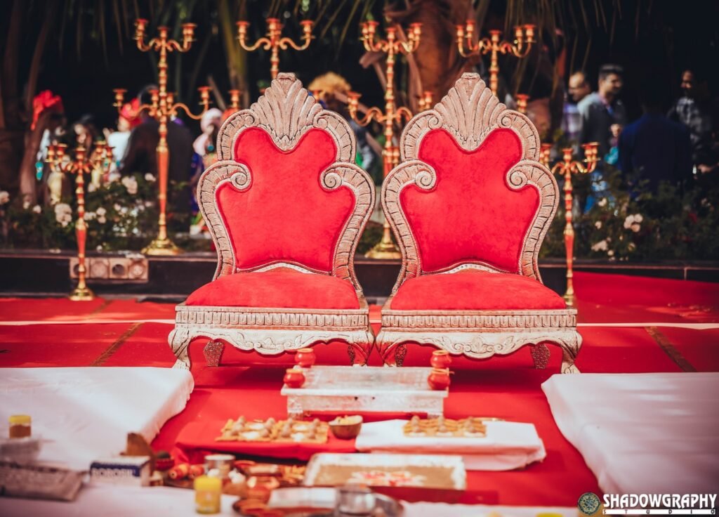 A decorated wedding stage with red seating for the couple