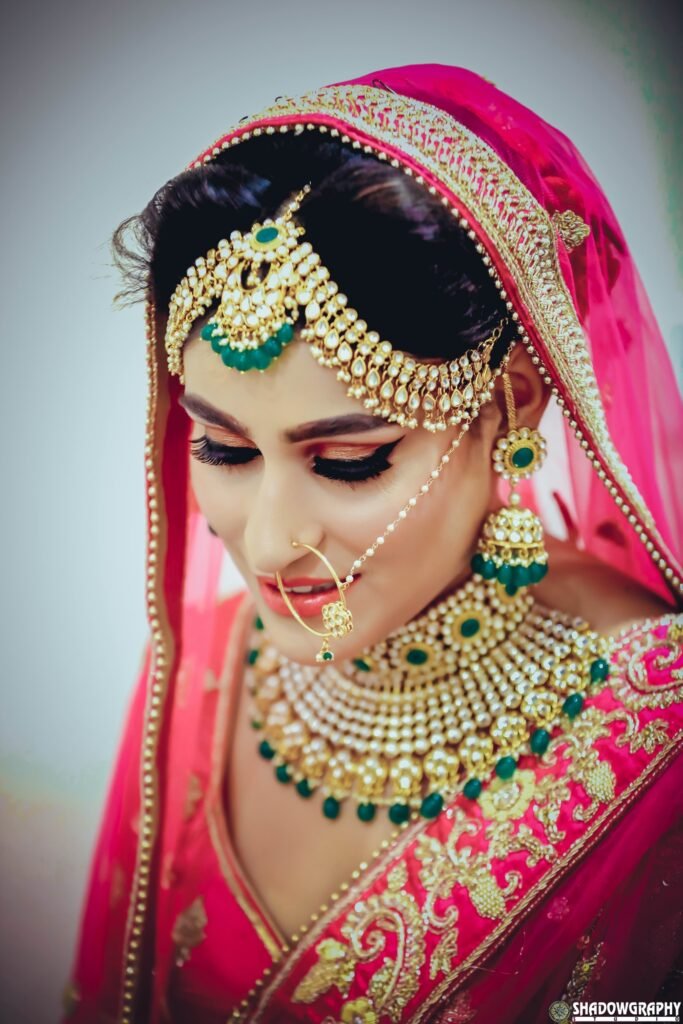 Bridal portrait with traditional jewellery, a pink dupatta and a green-stone necklace