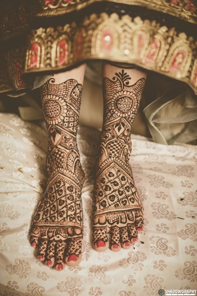 Close-up of intricate bridal mehndi on feet against embroidered fabric