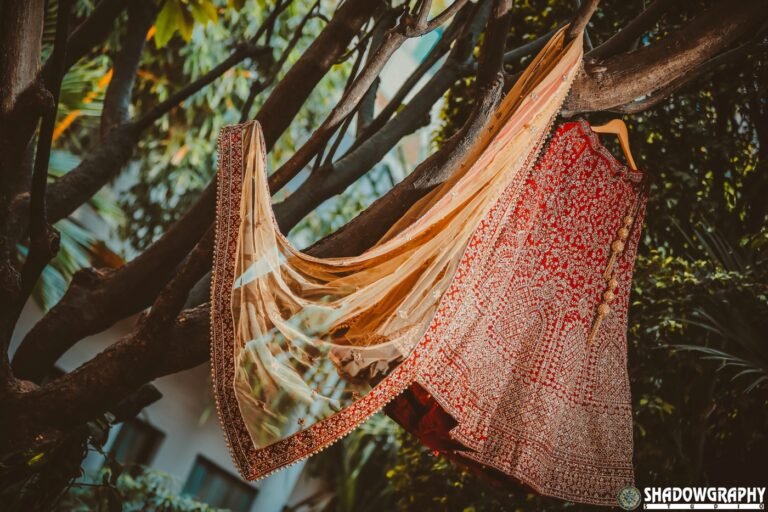 Red embroidered bridal lehenga photographed outdoors by Shadowgraphy Studio ahead of a wedding celebration