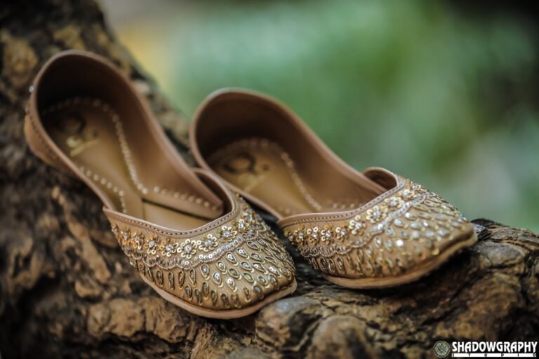 Embroidered bridal juttis photographed on a textured wooden surface, from a Shadowgraphy Studio wedding