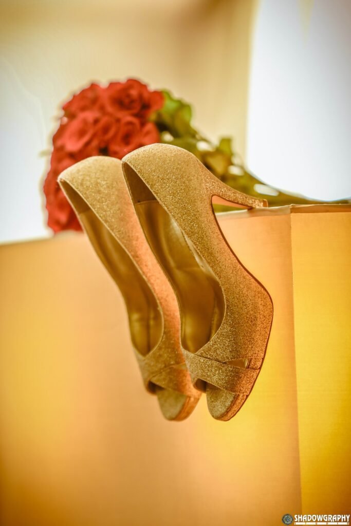 Gold bridal heels hanging beside marigold flowers in warm natural light
