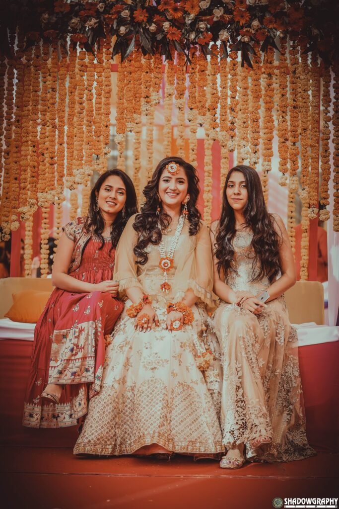 Guests in festive outfits posing together at a floral backdrop photo corner
