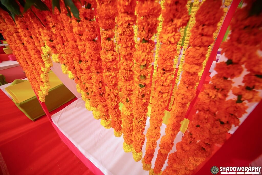 Hanging marigold garlands used as a colourful photo backdrop at a wedding