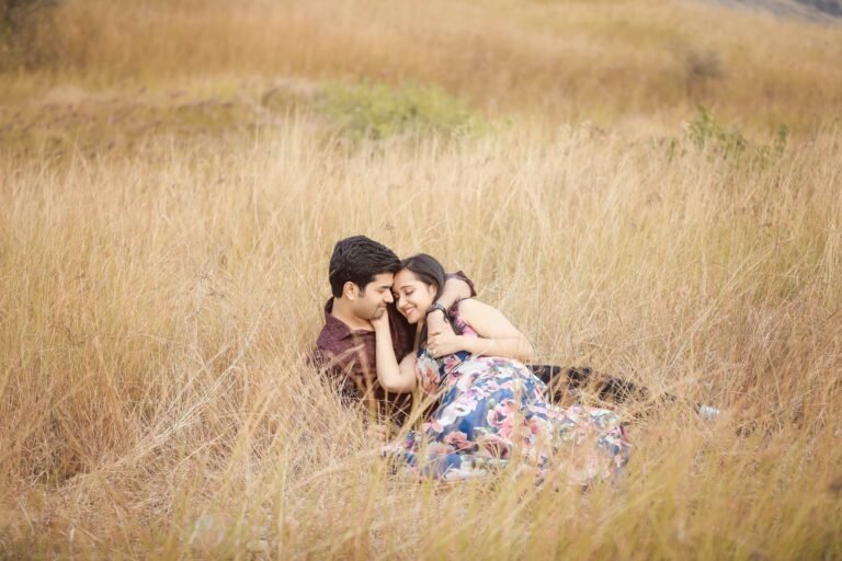 Couple sitting together in tall golden grass during a pre-wedding shoot