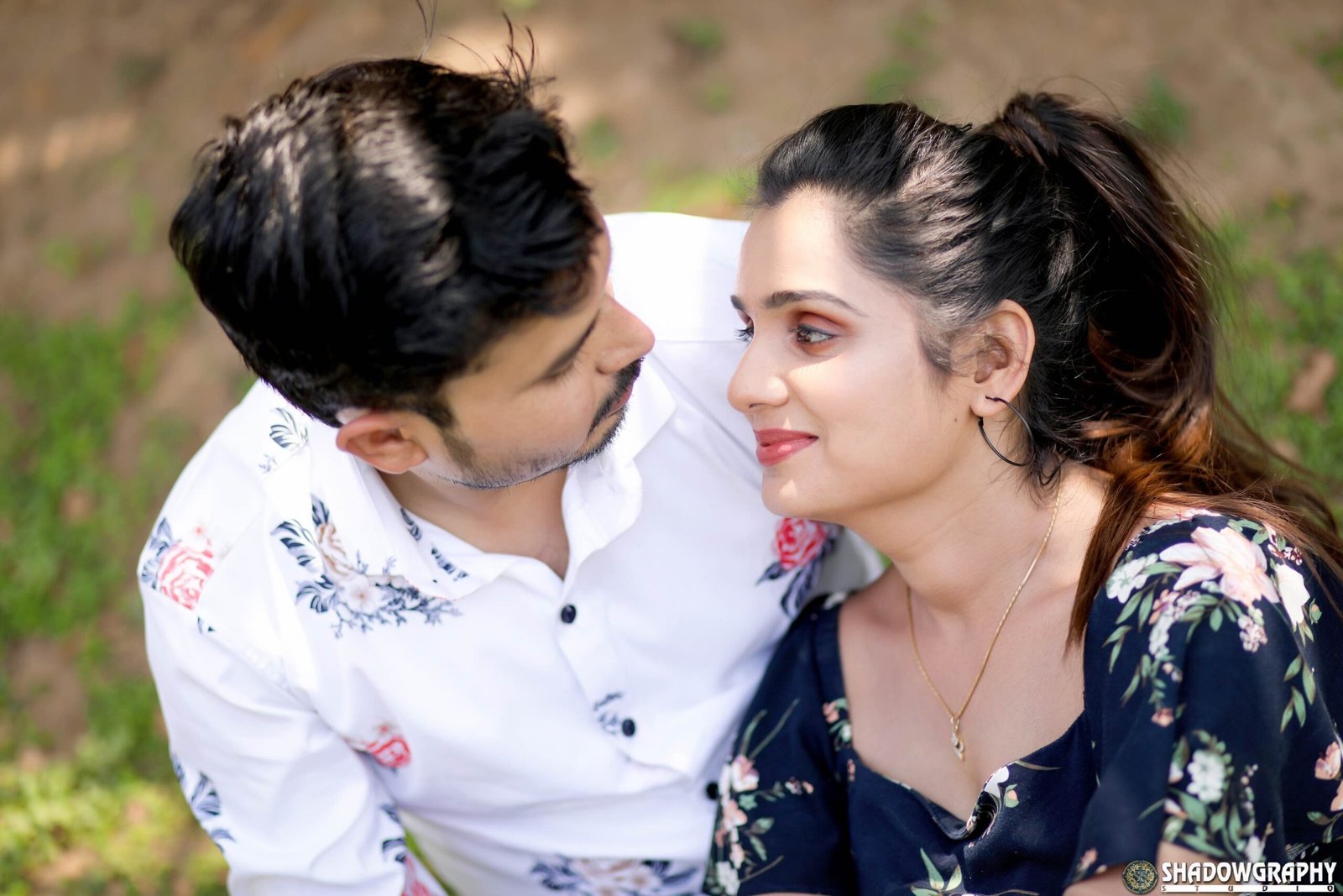 Close portrait of a couple smiling at each other with soft greenery behind