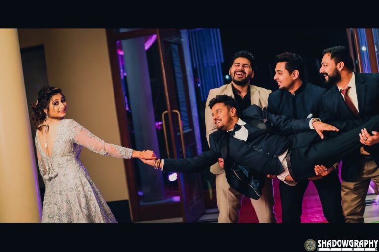 Groomsmen lifting the groom during a fun reception-stage group photo as the bride reaches for his hand