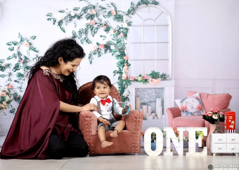Mother playing with her one-year-old son during a first birthday photoshoot with ONE letter props