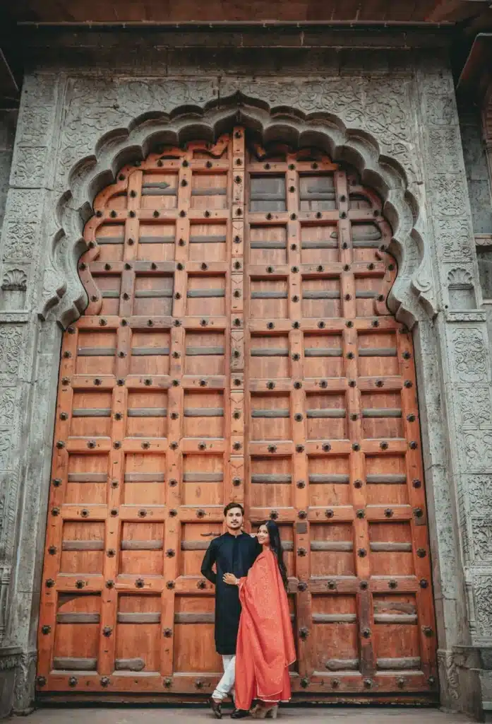 Couple beside a carved wooden door at Rajwada