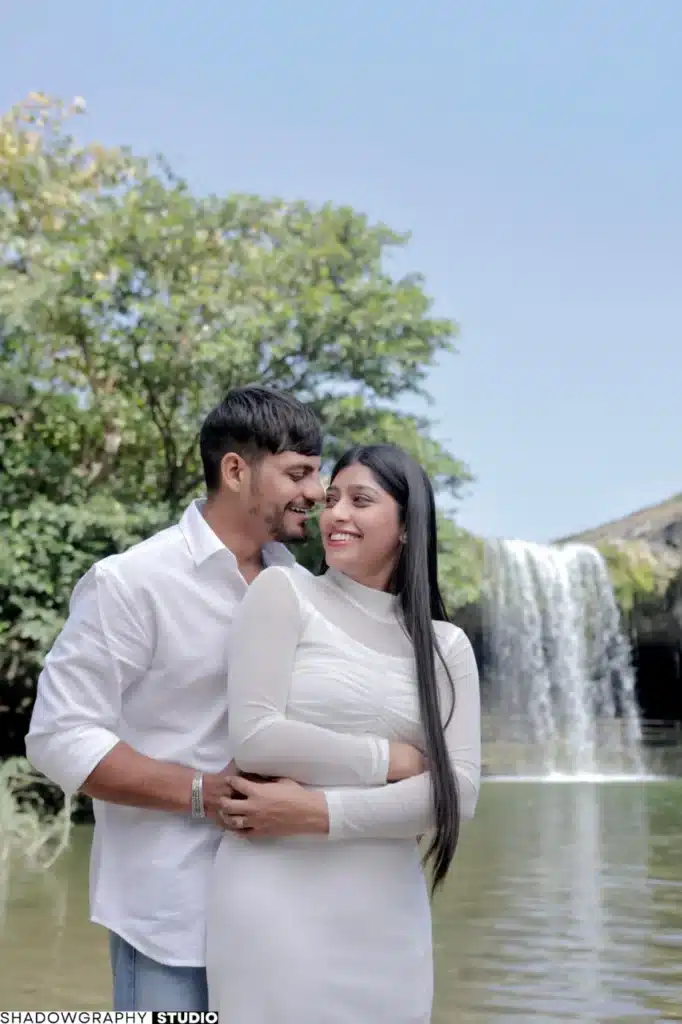 Couple in white outfits beside the waterfall at Ganga Mahadev
