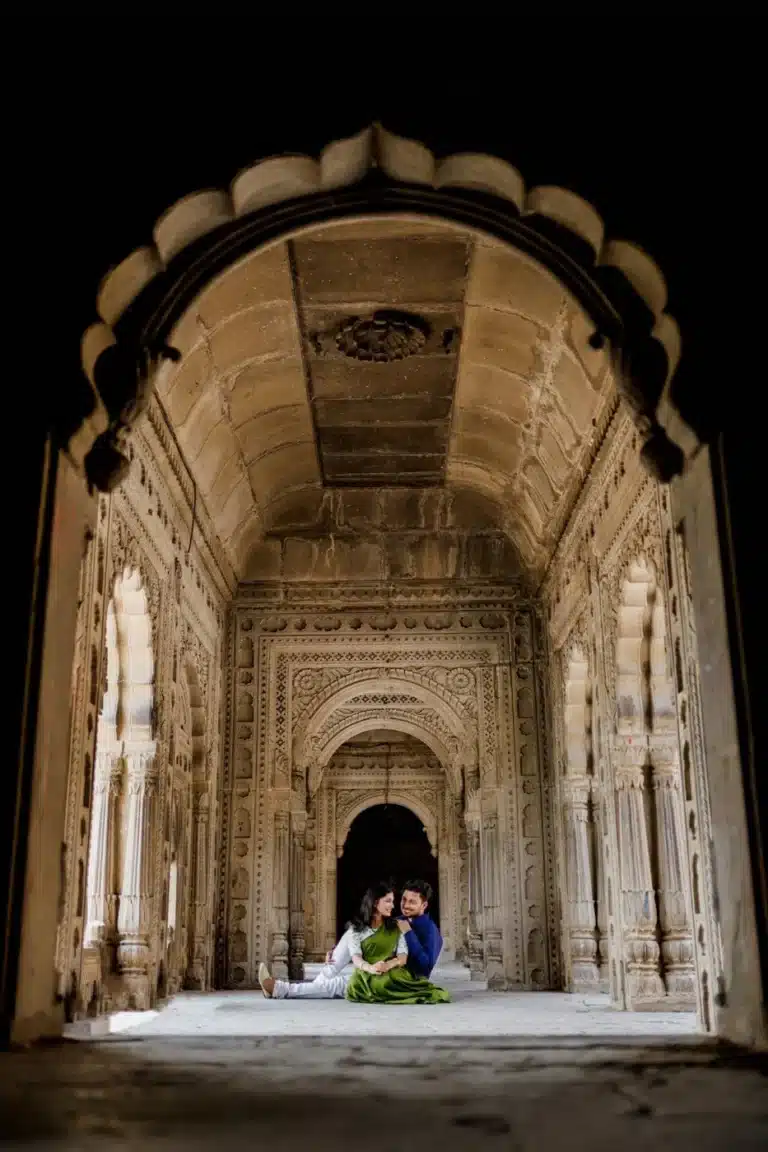 Couple seated together inside an intricately carved stone hall in Maheshwar, lit warmly at night, by Shadowgraphy Studio