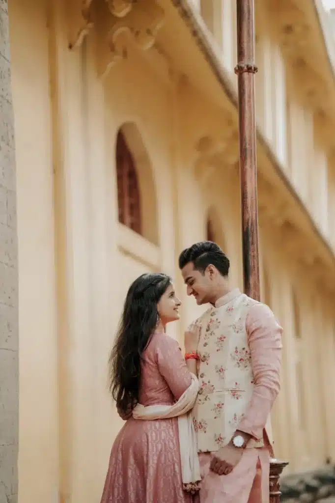 Couple in pink outfits beside a stone pillar at Rajwada