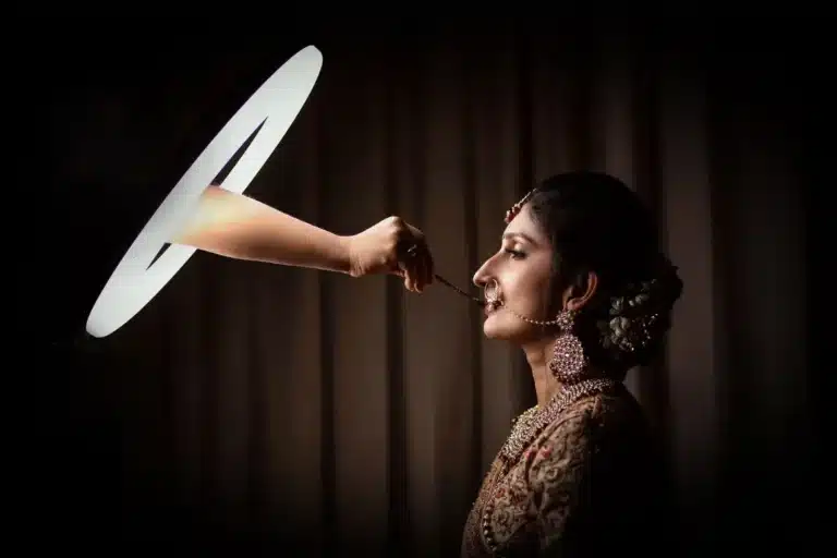 Candid bridal portrait of a bride in profile lit by a circular light on a dark backdrop