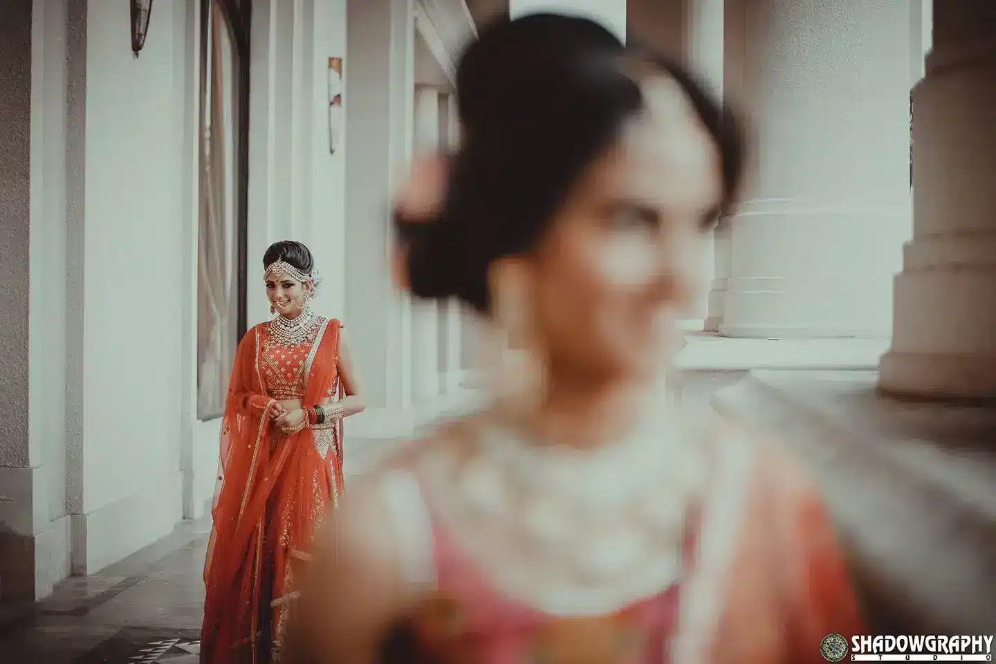 Soft-focus portrait of a bride in an orange lehenga in a bright room